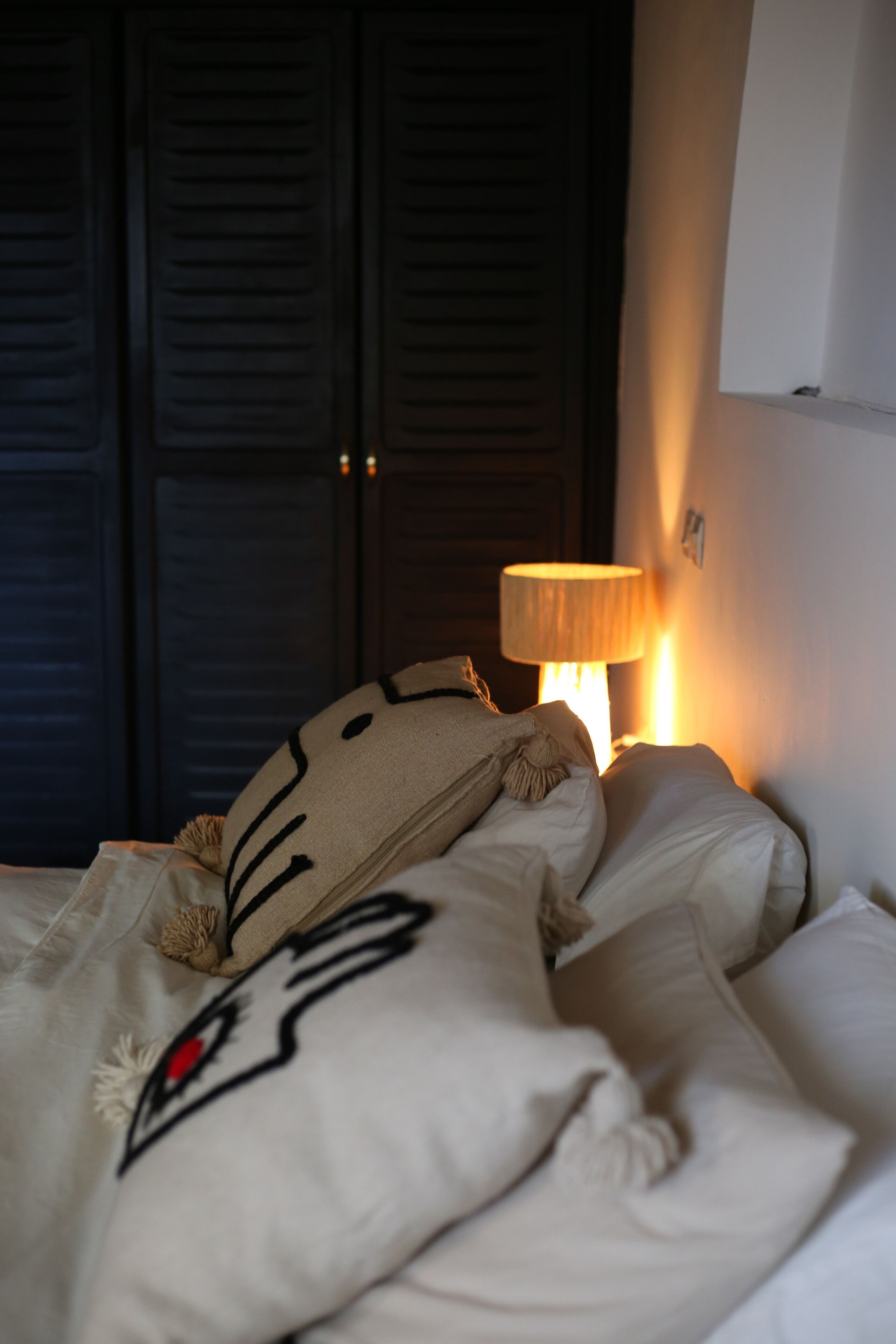 Une chambre à coucher avec un lit, une lampe et une armoire.