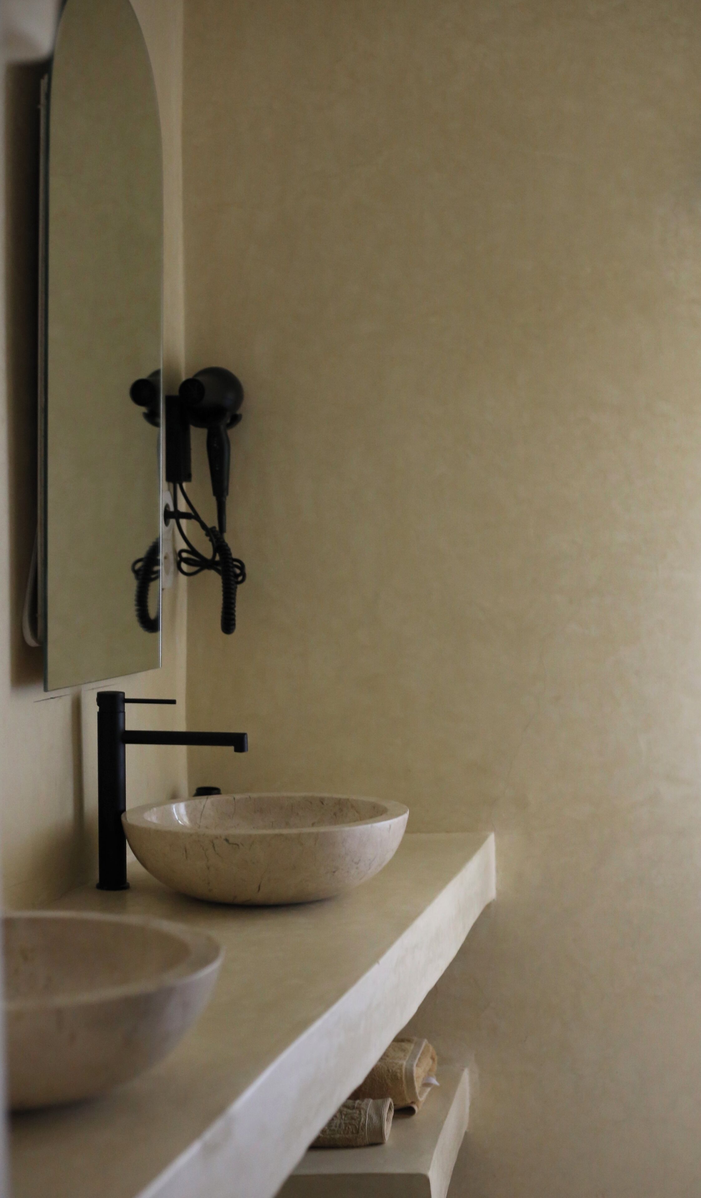A bathroom with a large mirror, a black faucet, and a beige sink.