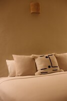 Una cama con dos almohadas, una lisa y otra con un diseño facial.