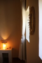 Una habitación con una lámpara encendida, un espejo con flecos y una cortina entreabierta.