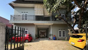 A two-story building with a balcony, a gated driveway, and two parked cars. - Hotel O Pondok Bulo Ugi Syariah Near SD Negeri 185 Pinrang (Binanga Karaeng)