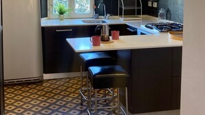 Una cocina moderna con una isla central, armarios negros, un refrigerador de acero inoxidable y un suelo con diseño.