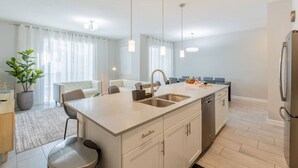 A modern kitchen with a central island, stainless steel appliances, and pendant lighting. - Family 4BR w/ Private Pool near Disney Parks! (Kissimmee)