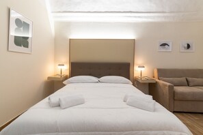 Une chambre d’hôtel avec un grand lit, deux tables de chevet avec des lampes, un canapé et des œuvres d’art murales.