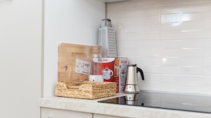 A kitchen with a wooden cutting board, a box of Gurmii yogurt, a kettle, and a grater on the counter. - Villari 48 Apartment - Appartamento 2 (Naples)