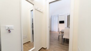 A hallway with a mirror, a door leading to a dining area, and a light switch on the wall. - Villari 48 Apartment - Appartamento 2 (Naples)