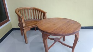 Une chaise et une table en bois se trouvent dans une pièce dont le sol est carrelé et dont le mur est uni.