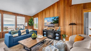 A living room with a blue sofa, a wooden coffee table, and a fireplace. - Stunning Home: Spacious layout, perfect for gathering with friends or family. (Rockaway Beach)