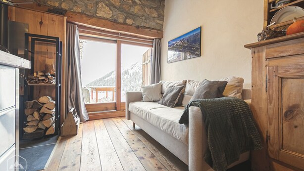 A cozy living room with a sofa, wooden cabinets, and a fireplace. - Le Chalet du Papote (Aussois)