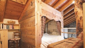 A cozy wooden cabin room with a bed, a chair, a bookshelf, and a table. - Le Chalet du Papote (Aussois)