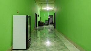 Corredor com paredes verdes e uma geladeira branca à esquerda.