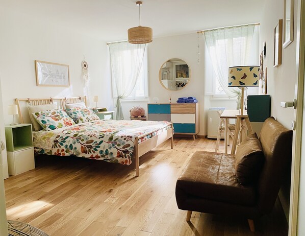 Un dormitorio con cama, cómoda, escritorio, silla y sofá.