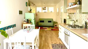 Una cocina compacta con zona de comedor, un sofá verde y una mesita con hervidor.