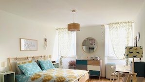 Un dormitorio con una cama de madera, un escritorio, una silla, una lámpara y un espejo.
