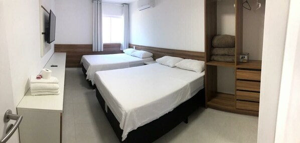 Habitación de hotel con dos camas, un escritorio, un televisor y un armario.