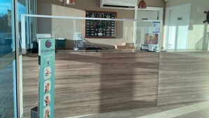 A reception area with a wooden reception desk, a framed menu board, and a sign for Golden Lake Alcohol Gel.