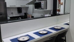 A modern kitchen with white cabinets, a microwave, and a dining area with a long table and chairs.