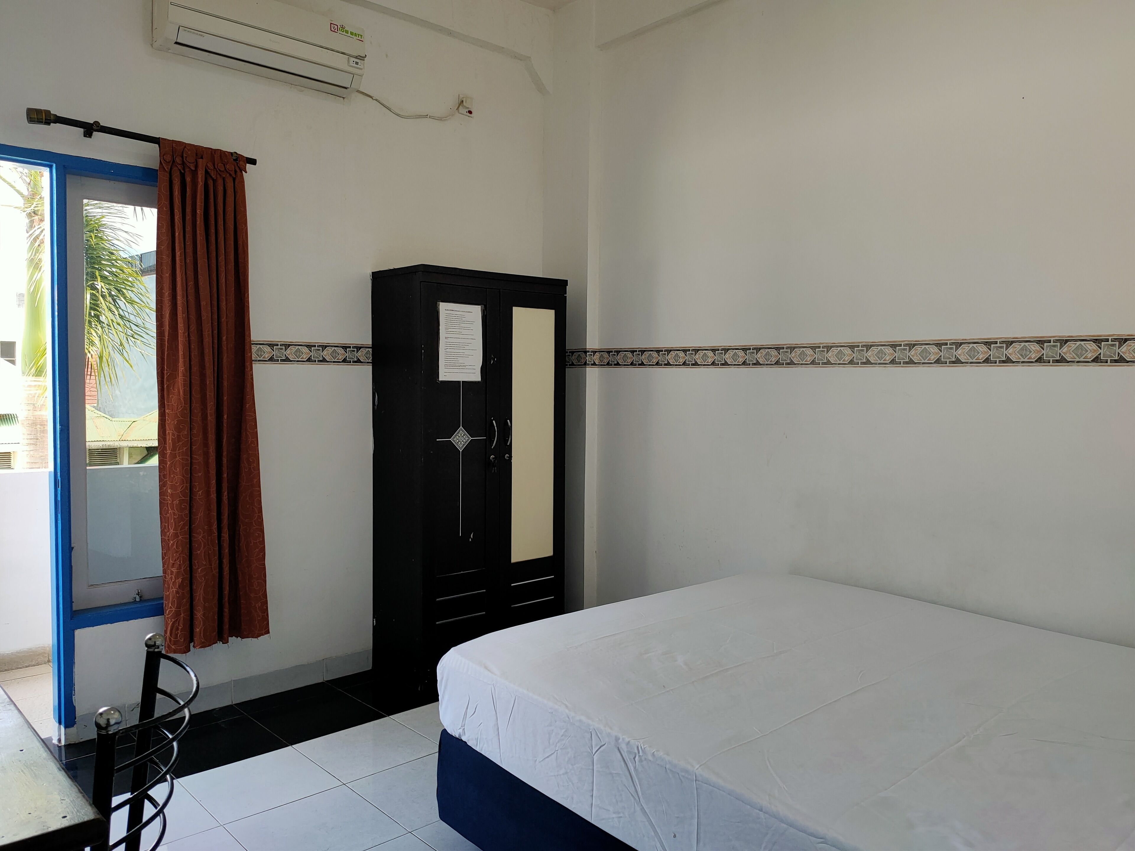 A room with a bed, a wardrobe, a curtain, and a window.