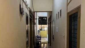 A narrow hallway with a bench, a door with a window, and a visible room in the background. - OYO 93412 Kost Irma Syariah Near UPTD SMP Negeri 8 Parepare (Parepare)