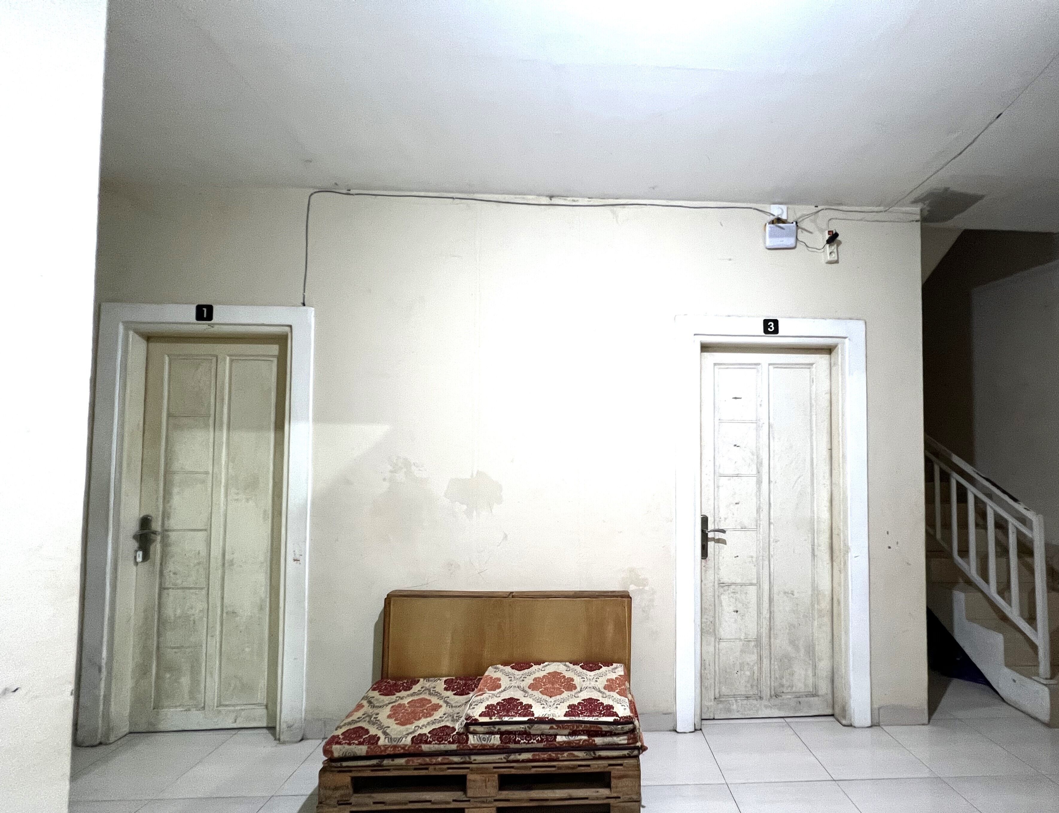A room with two doors, a wooden bench, and a white ceiling.