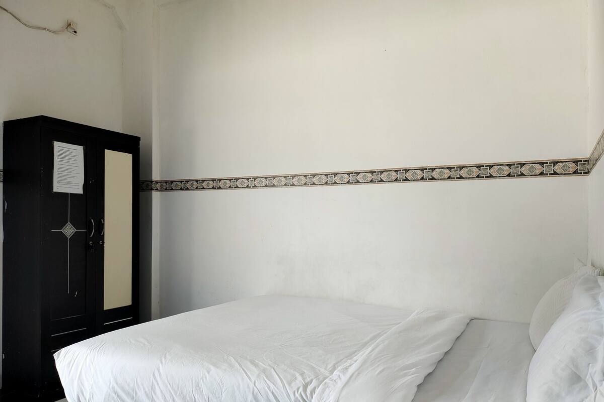 Una habitación sencilla con una cama, un armario y un detalle decorativo en la pared.