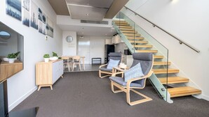 A modern interior with a staircase, seating area, and kitchen.