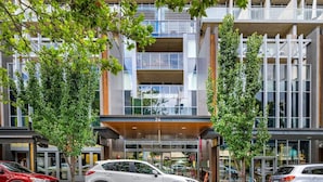 A modern building with a glass facade, numbered 24, featuring a central entrance with a wooden canopy.