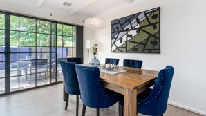 A dining area with a wooden table, blue upholstered chairs, a chandelier, and a large abstract painting on the wall. - 4BR/2BA House Nestled in a Quiet Spot in Dickson (Dickson)