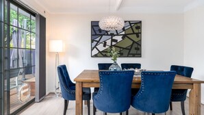 A dining area with a wooden table, six blue upholstered chairs, a chandelier, and a modern abstract painting on the wall. - 4BR/2BA House Nestled in a Quiet Spot in Dickson (Dickson)