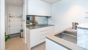 A modern kitchen with white cabinets, a stainless steel sink, and a built-in oven. - 2BR Apartment near Parliament House (Barton)