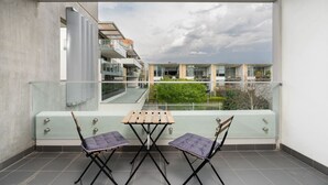 Un balcon doté d’une balustrade en verre, de deux chaises et d’une petite table.