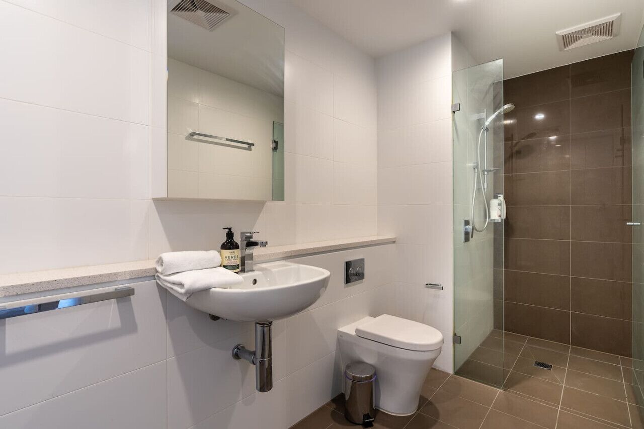 Een moderne badkamer met een witte wastafel, een toilet en een douchecabine van glas.