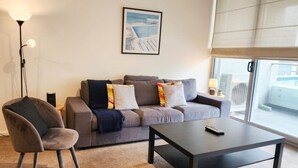 Un salon moderne avec un canapé gris, une table basse noire et un fauteuil gris.