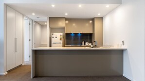Une cuisine moderne dotée d’un îlot central, d’appareils électroménagers intégrés et d’un éclairage encastré.