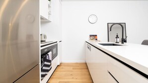 Een moderne keuken met witte kasten, een roestvrijstalen koelkast, een magnetron en een gootsteen met een zwarte kraan.