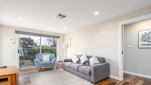 A modern living room with a grey sofa, a blue armchair, and a wooden coffee table.