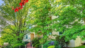 A residential building with a well-maintained garden, a staircase leading to the entrance, and a clear sky. - 2BR/2BA Apt w/ Dedicated Workspace & Free parking! (Griffith)
