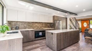 Una cocina moderna con una isla central, horno integrado y electrodomésticos de acero inoxidable.