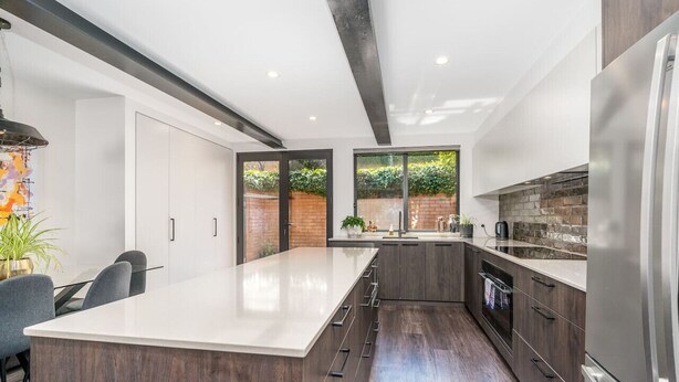 Una cocina moderna con una isla grande, armarios de madera oscura y un refrigerador de acero inoxidable.