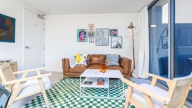 A living room with a checkered floor, a brown leather sofa, and a white coffee table. - 2BR Penthouse w/ Breathtaking View! (Braddon)