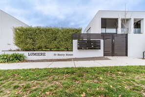 A modern building with a white facade, a black gate, and a sign reading "LUMIERE 70 Henty Street". - 2-Storey Lumiere Townhouse w/ Private Courtyard (Braddon)