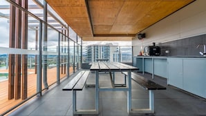 A modern kitchen with a large window, a wooden ceiling, and a view of the cityscape. - 2BR Apt in the heart of the Gungahlin Town Centre! (Gungahlin)