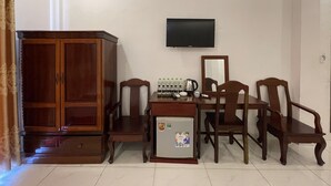 Un coin repas comprenant un buffet en bois, une table avec des chaises, un réfrigérateur et un téléviseur fixé au mur.