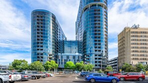 Een modern gebouw met een gebogen gevel, meerdere balkons en een parkeerplaats met auto's.