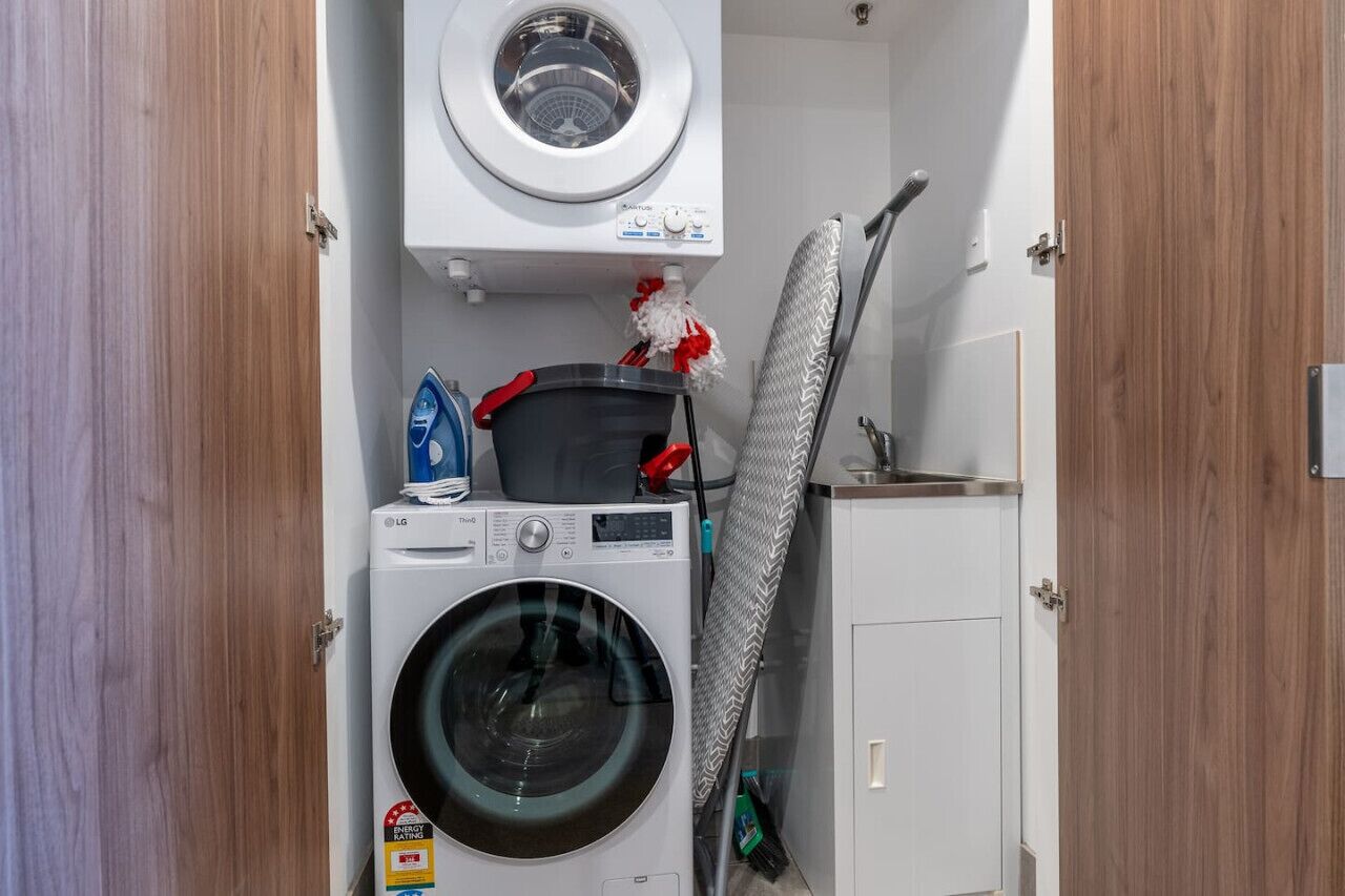 Een kleine wasruimte met een voorlader wasmachine, een droger en een ophangrek.