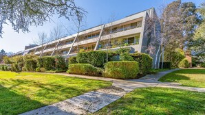 Un edificio moderno con techo plano, múltiples ventanales y un césped bien cuidado con un sendero hacia la entrada.