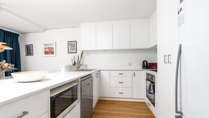 Una cocina moderna con armarios blancos, encimera de madera y electrodomésticos de acero inoxidable.