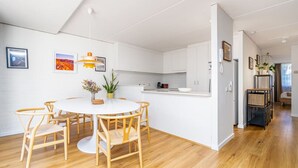 Una cocina moderna con armarios blancos, una mesa redonda de comedor con sillas de madera y una pequeña isla con un lavamanos.