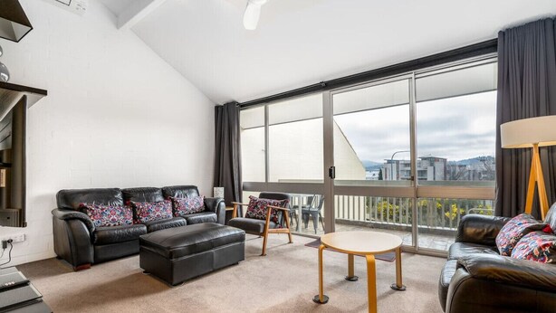 A modern living room with a black leather sofa, a round coffee table, and a balcony with a city view. - 3BR Loft Apt 1min to Kingston Foreshore! (Kingston)