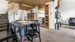 A modern kitchen with wooden cabinets, a dining area with a table and chairs, and a staircase leading to another level. - 3BR Loft Apt 1min to Kingston Foreshore! (Kingston)